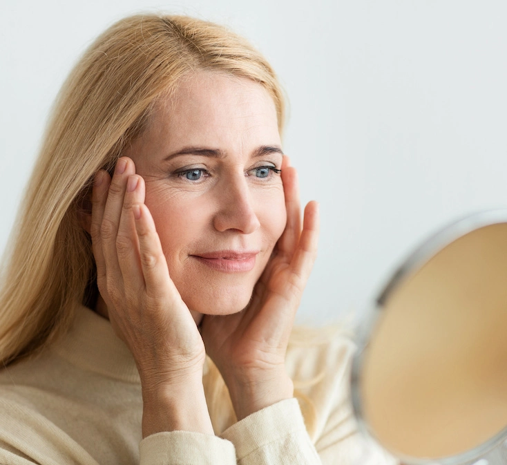 mature woman looking in the mirror at her skin