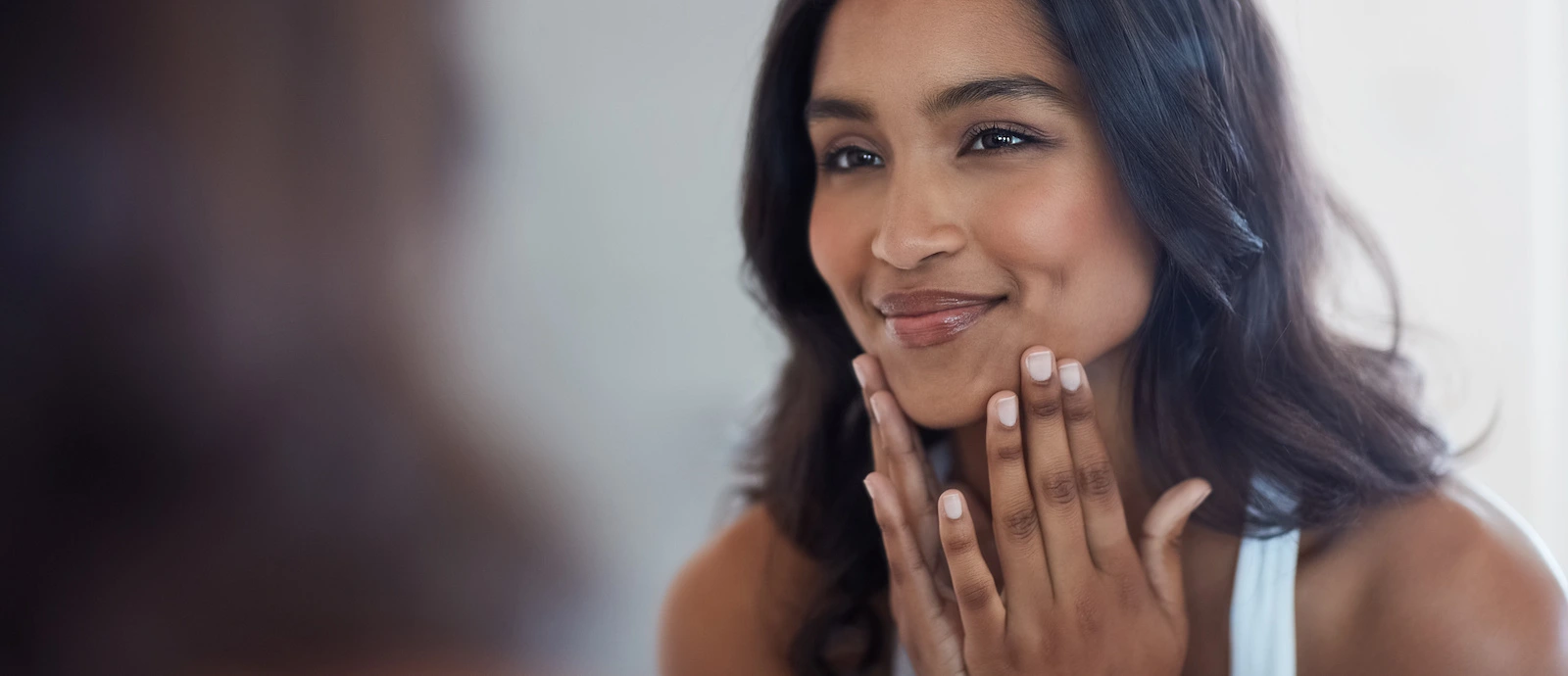 beautiful woman looking in the mirror at her skin