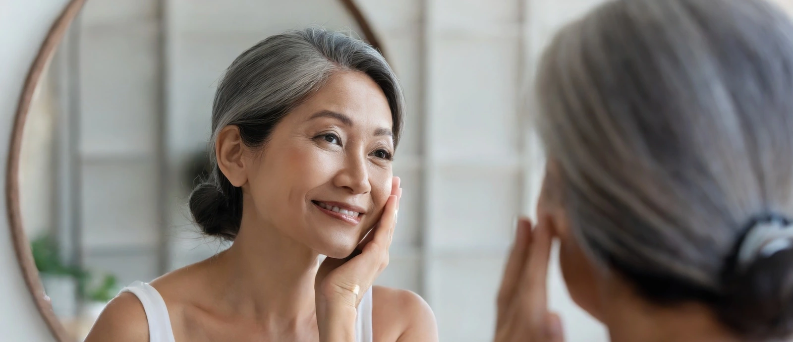 mature woman looking at her beautiful skin in the mirror