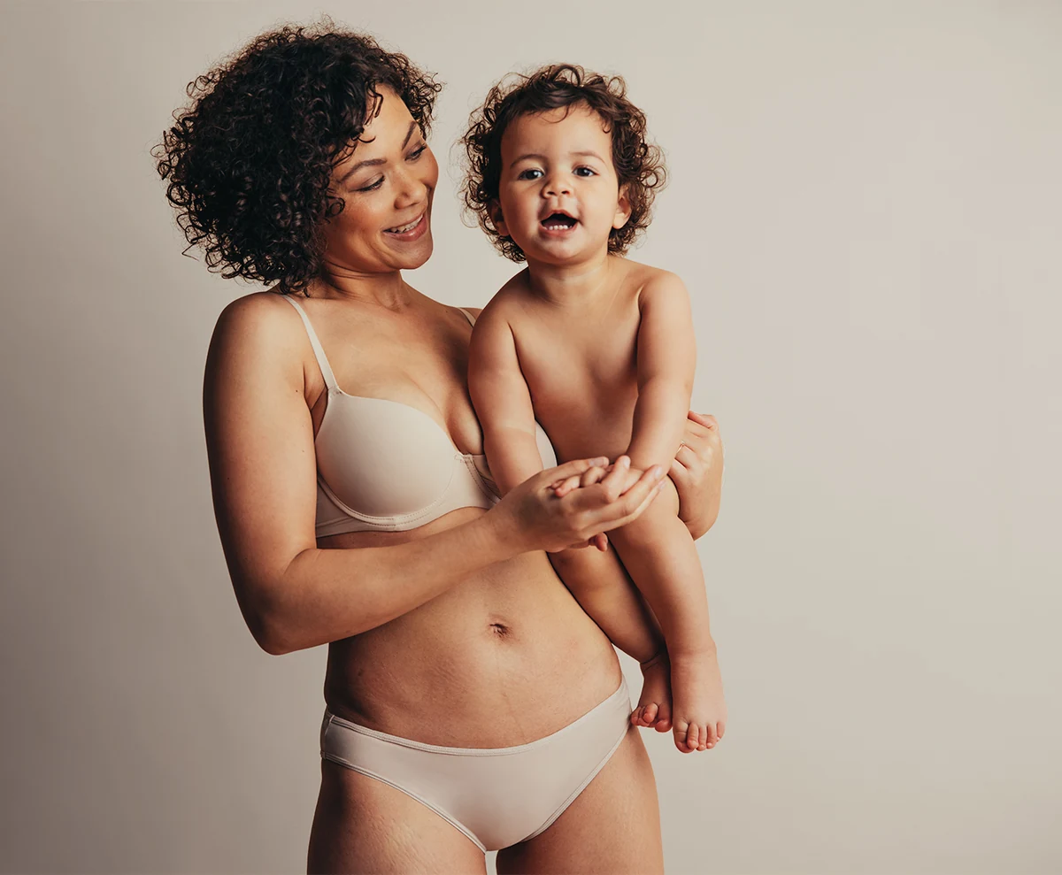 postpartum woman in comfortable underwear holding baby