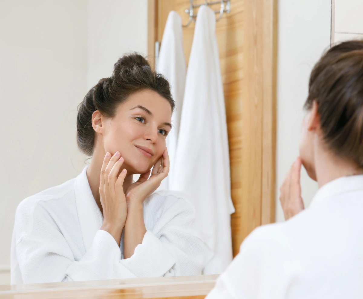 woman looking at her skin in the mirror